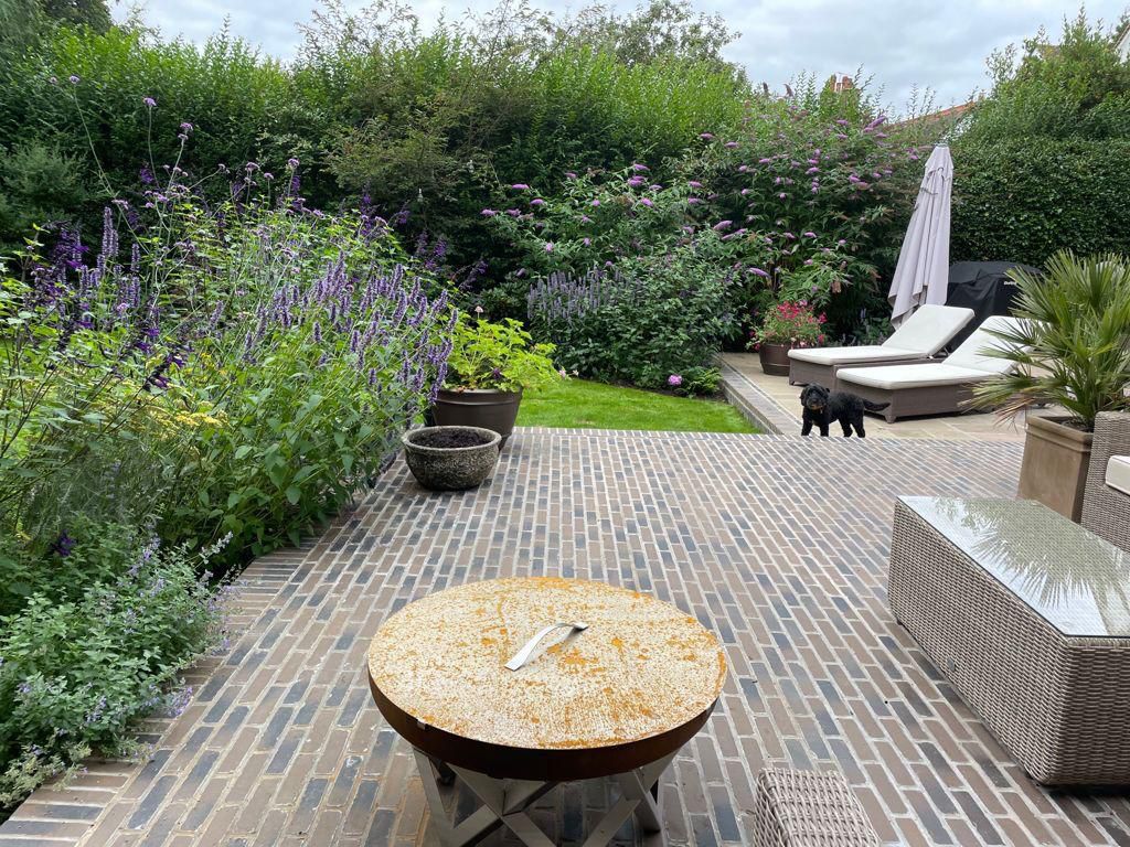 Cobblestone patio with brick edging and garden furniture
