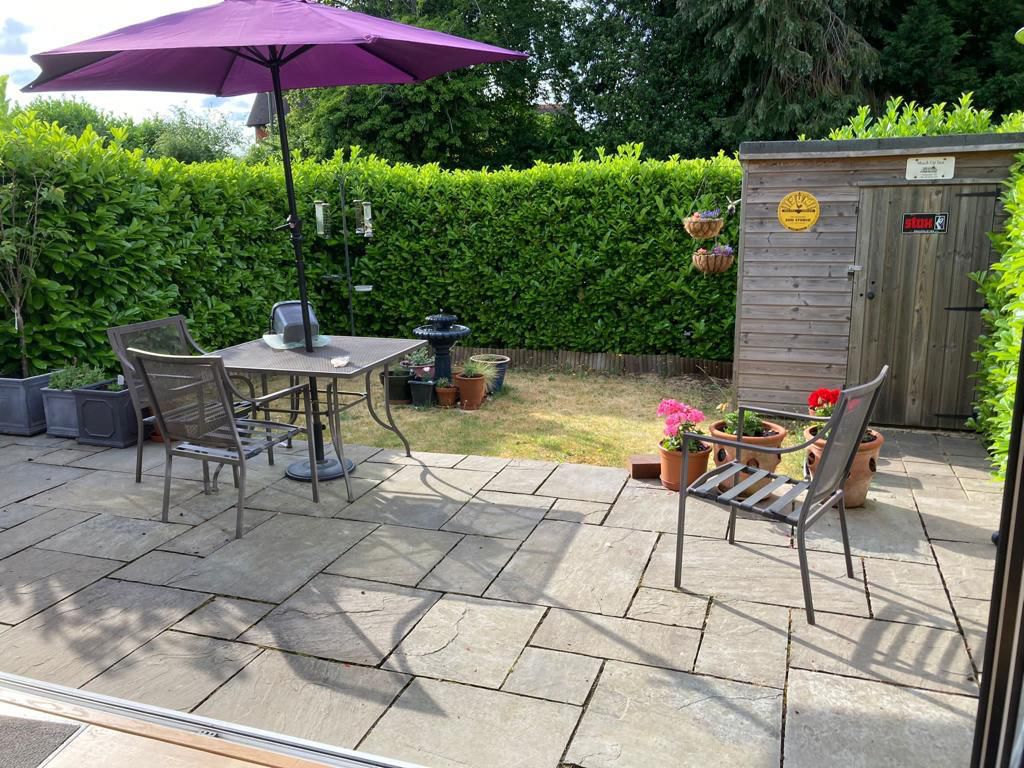 Natural stone patio with outdoor furniture in established garden